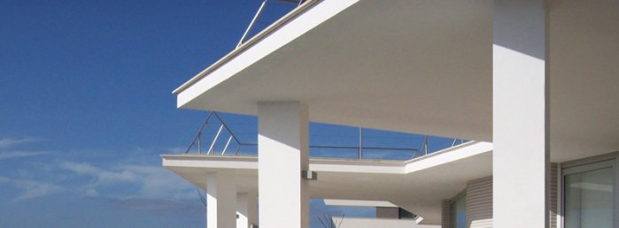 Modernistyczne dom z białymi balkonami oraz tarasami na dachu.